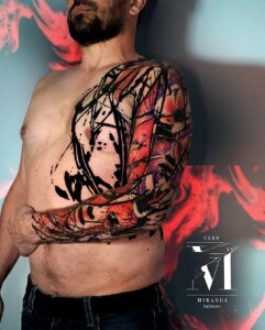 tatuaje en el pecho y tatuaje en el brazo en negro y rojo hecho por abel miranda, caras amapolas y lineas de tinta